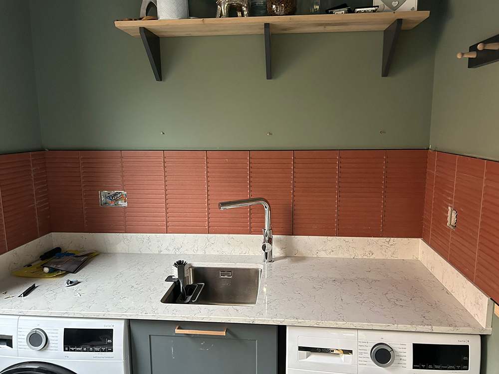 A utility room with green walls and terracotta tiles 