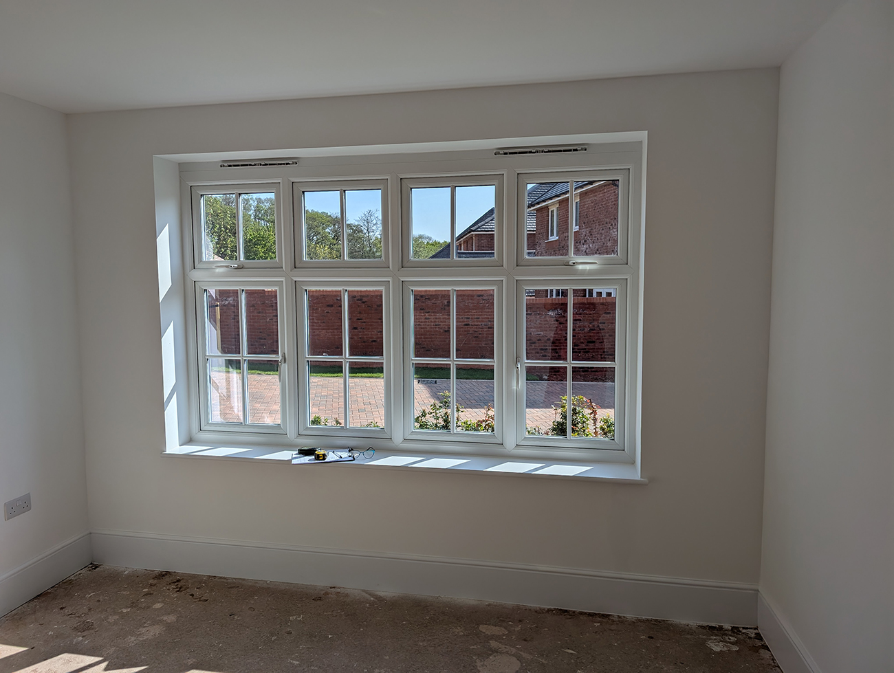 A living room with bare white walls and a large window 
