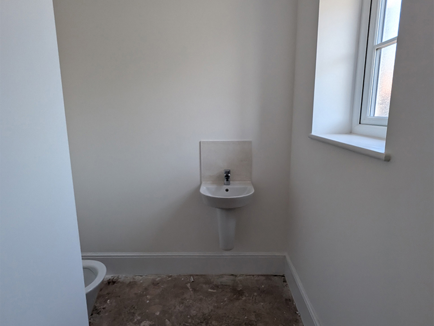 A downstairs toilet with all white walls and ceiling 
