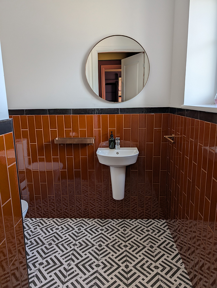 A downstairs toilet with a black and white patterned tiled floor