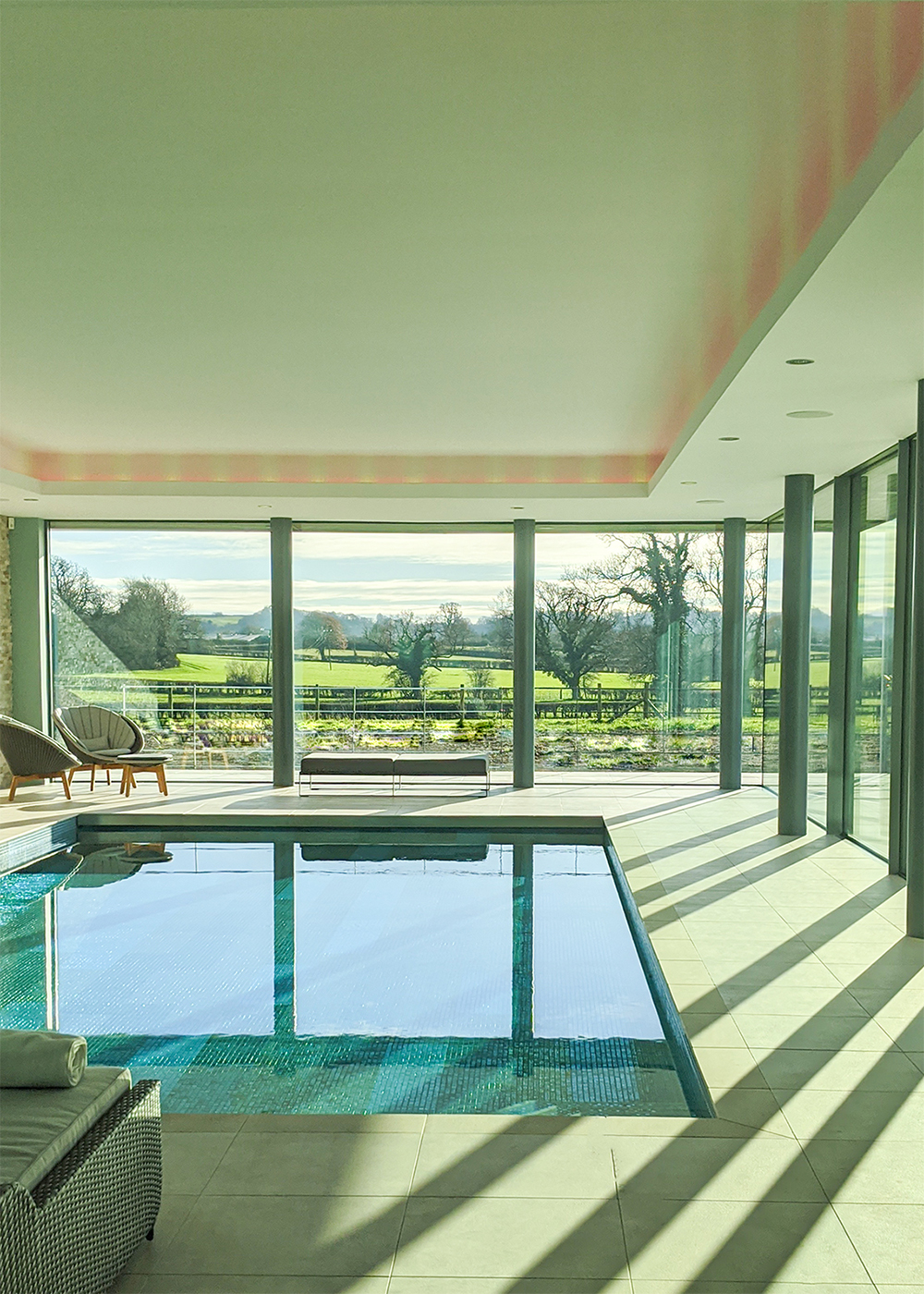 A photo of the finshed pool area with light streaming through the floor to ceiling windows.