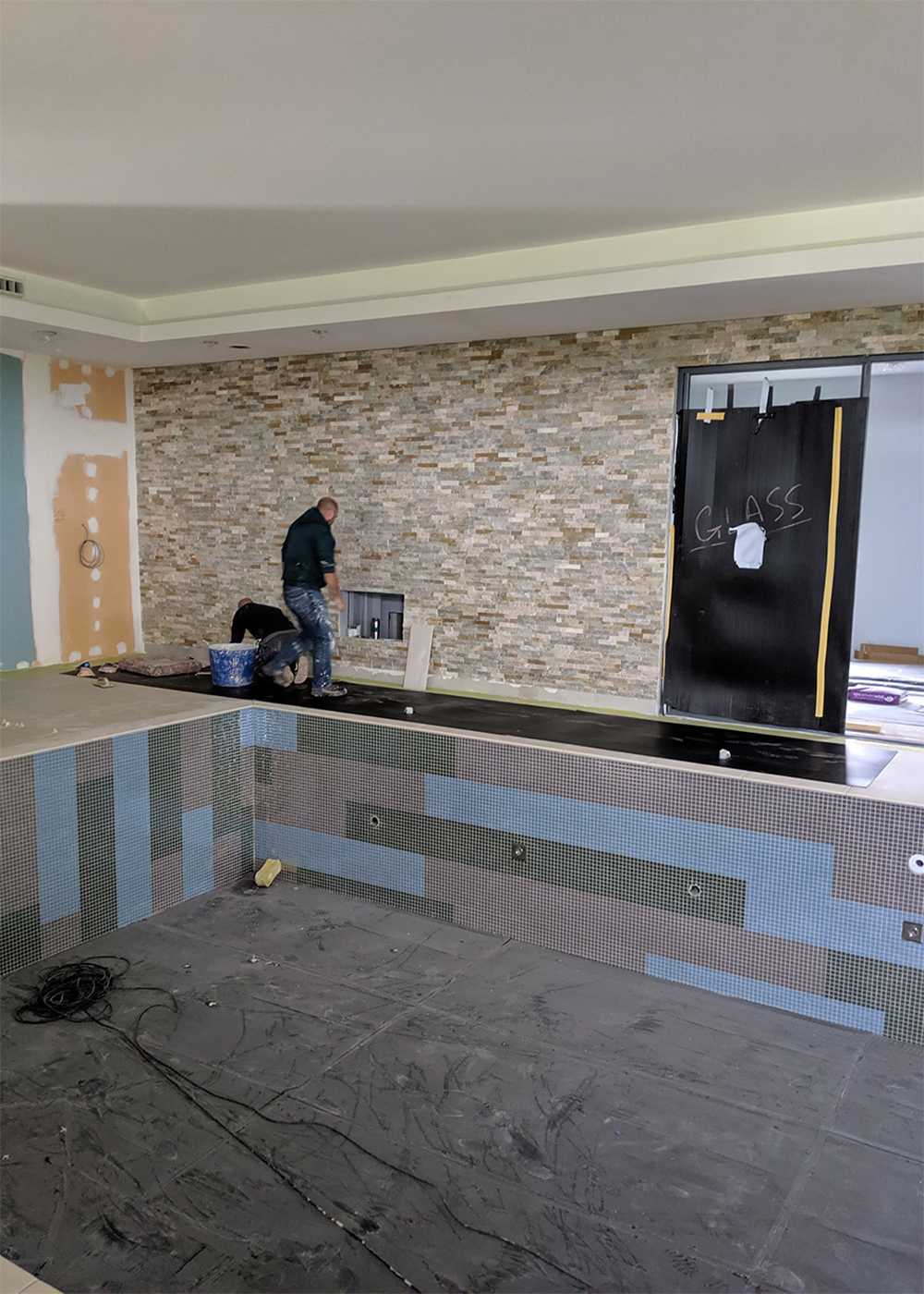 A photo of the chosen tiles being applied to the walls and tiles in the pool area.