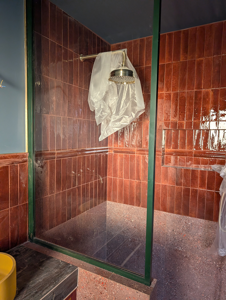 A photo of the tiled shower area with the rainfall shower head.