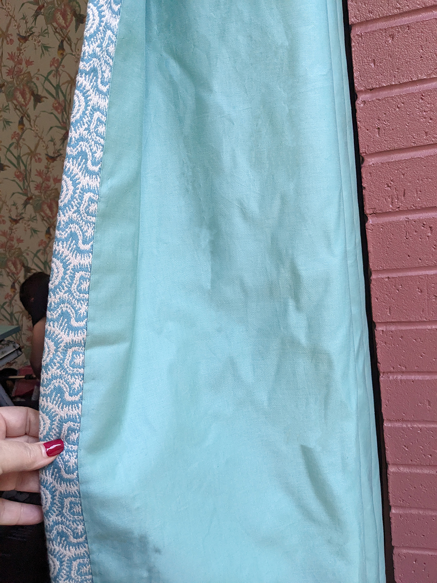 A photo of the back of a curtain, with a pretty green lining fabric.