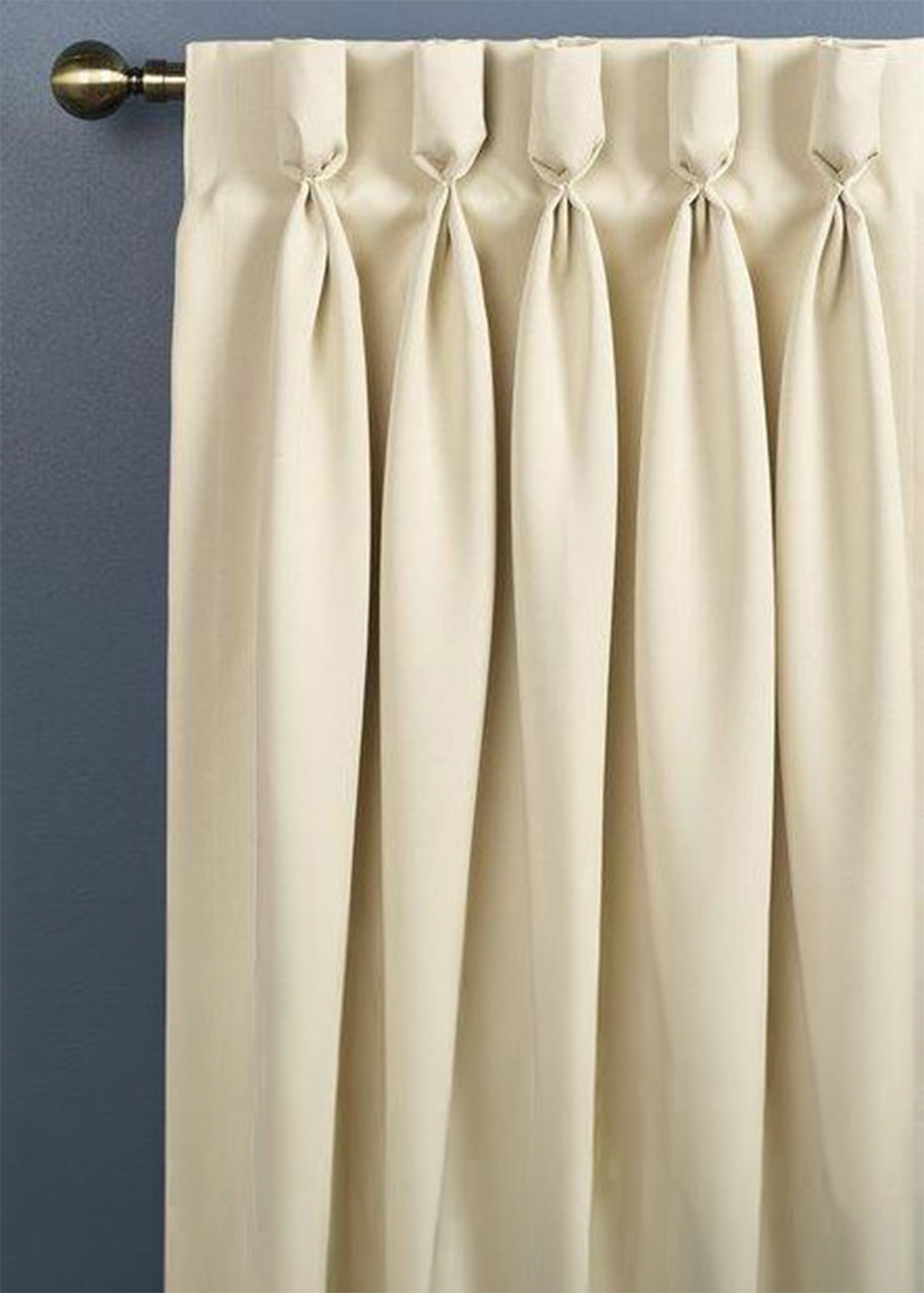 A photo of a cream curtain with a goblet heading on a brass pole.