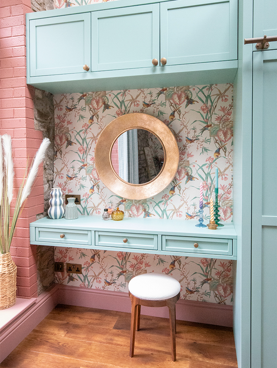A photo of the bedroom with built in green wardrobes and a dressing table, with the plug socket above the dressing table.