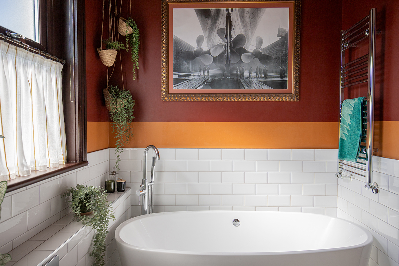 A photo of a bathroom with white tiles halfway up the walls, and a deep burgindy red paint above.