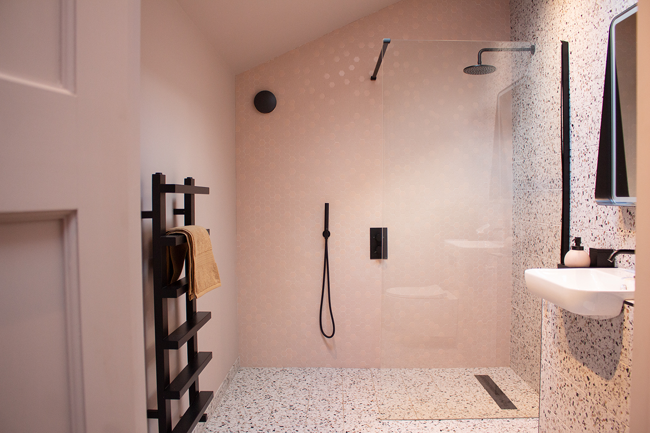 A photo of a pink bathroom with pink hexagon tiles and grout on the shower walls.