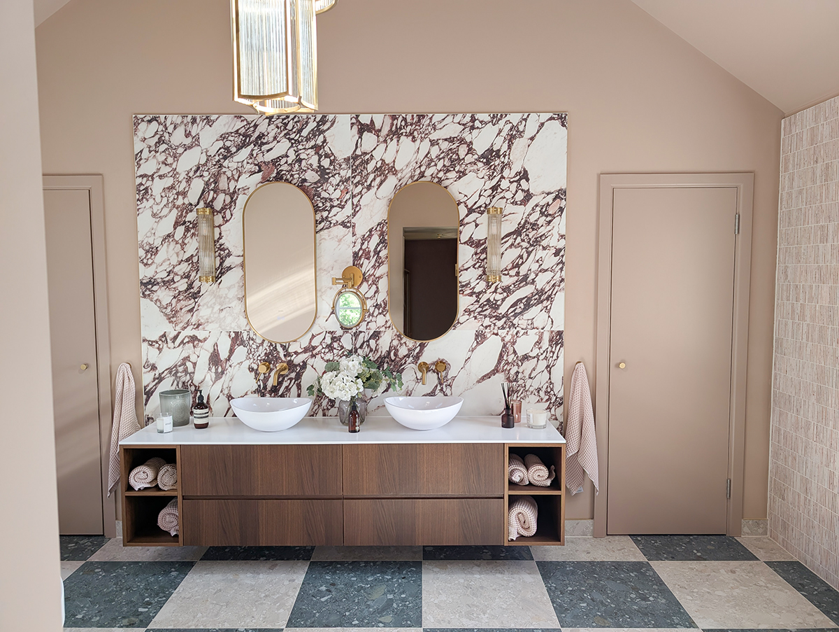 A photo of a large bathroom with a calacatta marble style porcelain tile behind the sink area.