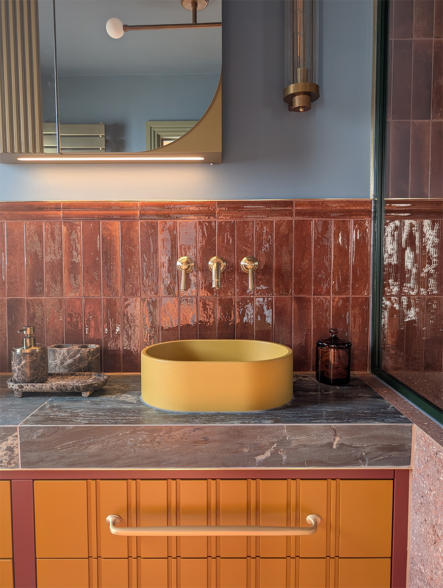 A photo of an en suite showing the half wall of tiles behind the sinks, with a border tile on top.
