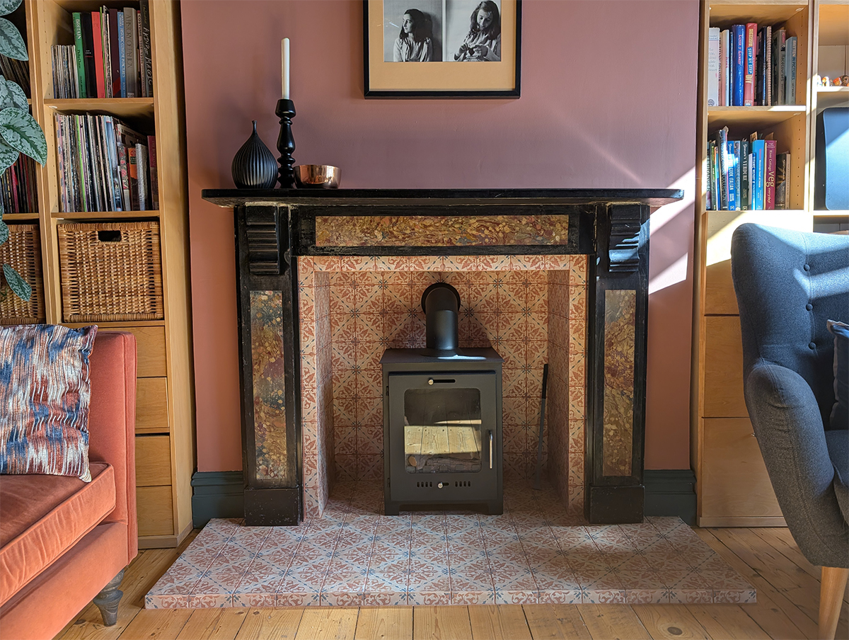 A photo of a wood burning stove with a patterned tile hearth and surround.