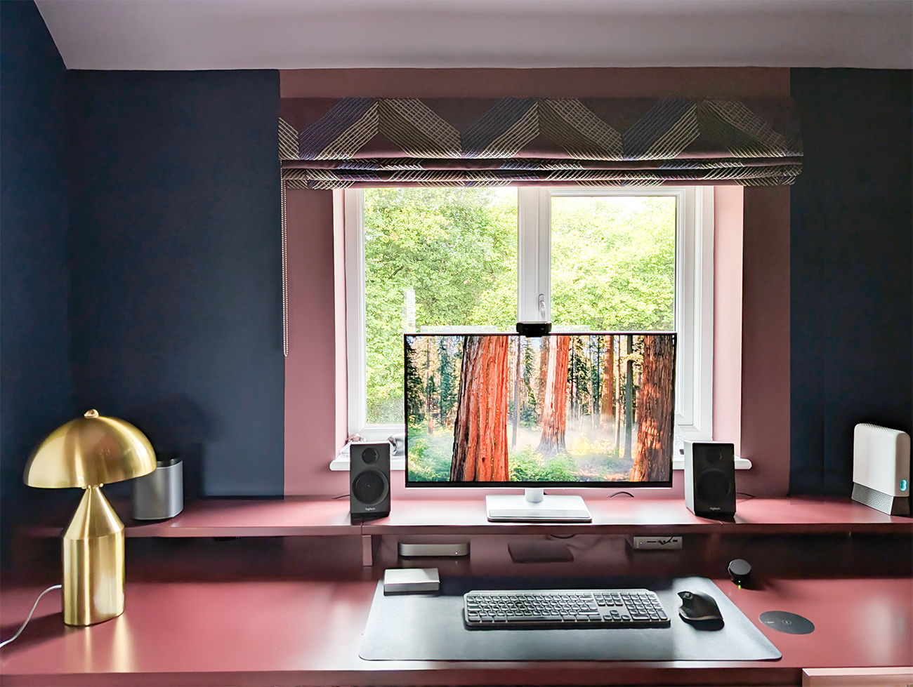 A close up photo of the window in the same room as before, with a burgundy bespoke desk  and lilac, navy and green walls.