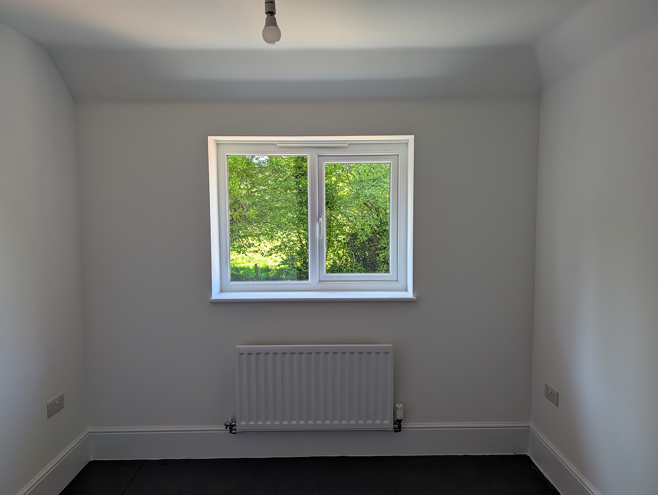 A before photo of a home office with bare white walls and no furniture.