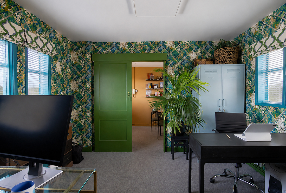 A photo showing the view from the larger office into the smaller one. This office has wallpapered green trellis patterned walls.