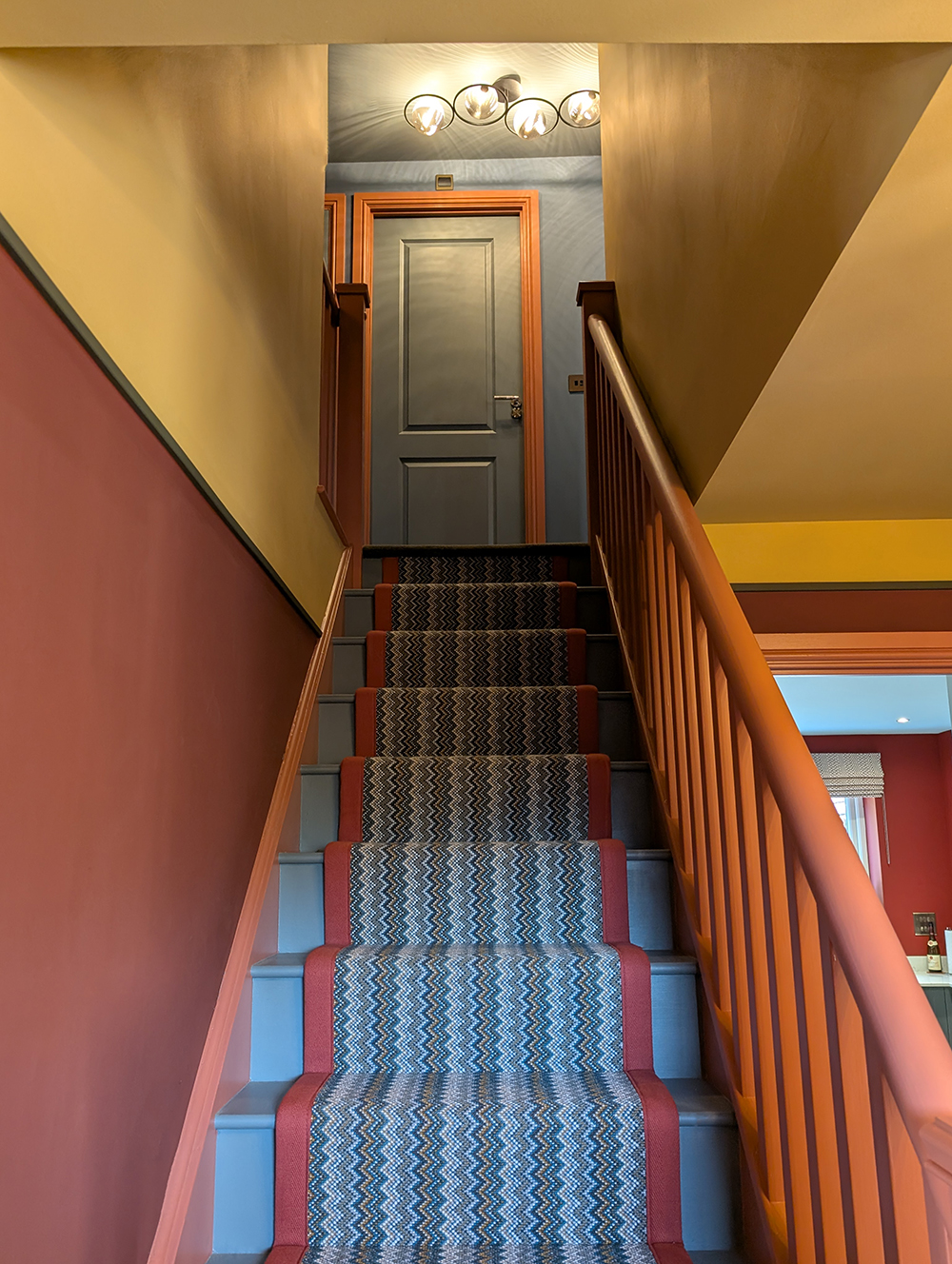 A colourful hallway in a new build house with a zig zag striped stair runner