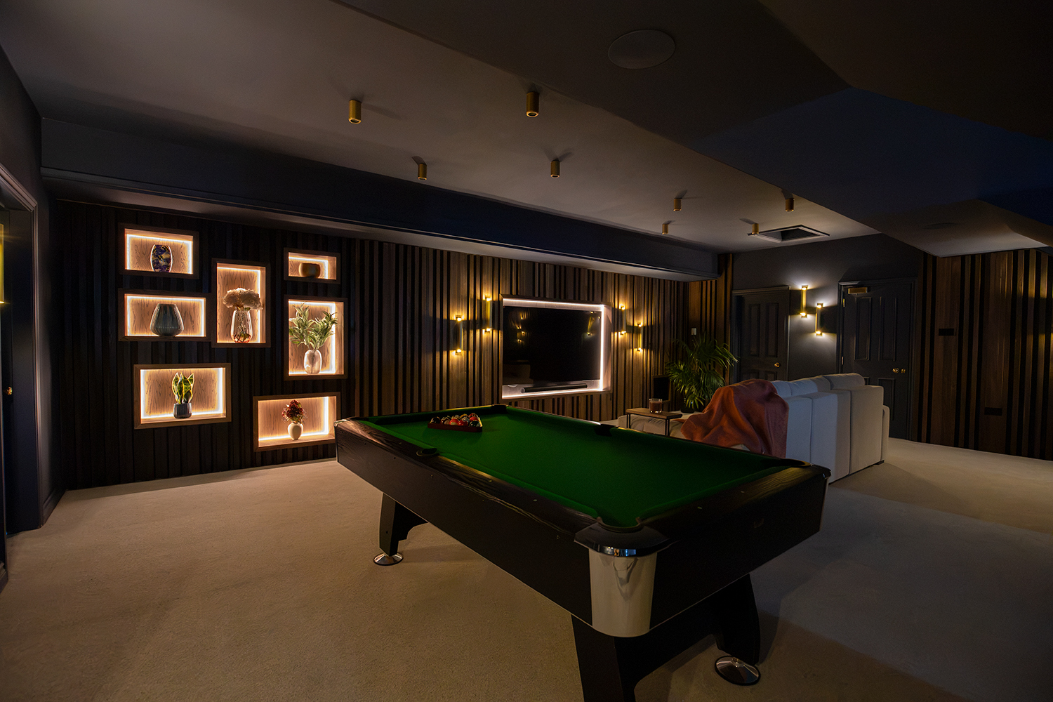 A view of the cinema room with the LEDs and wall lights dimmed, with the blinds drawn.