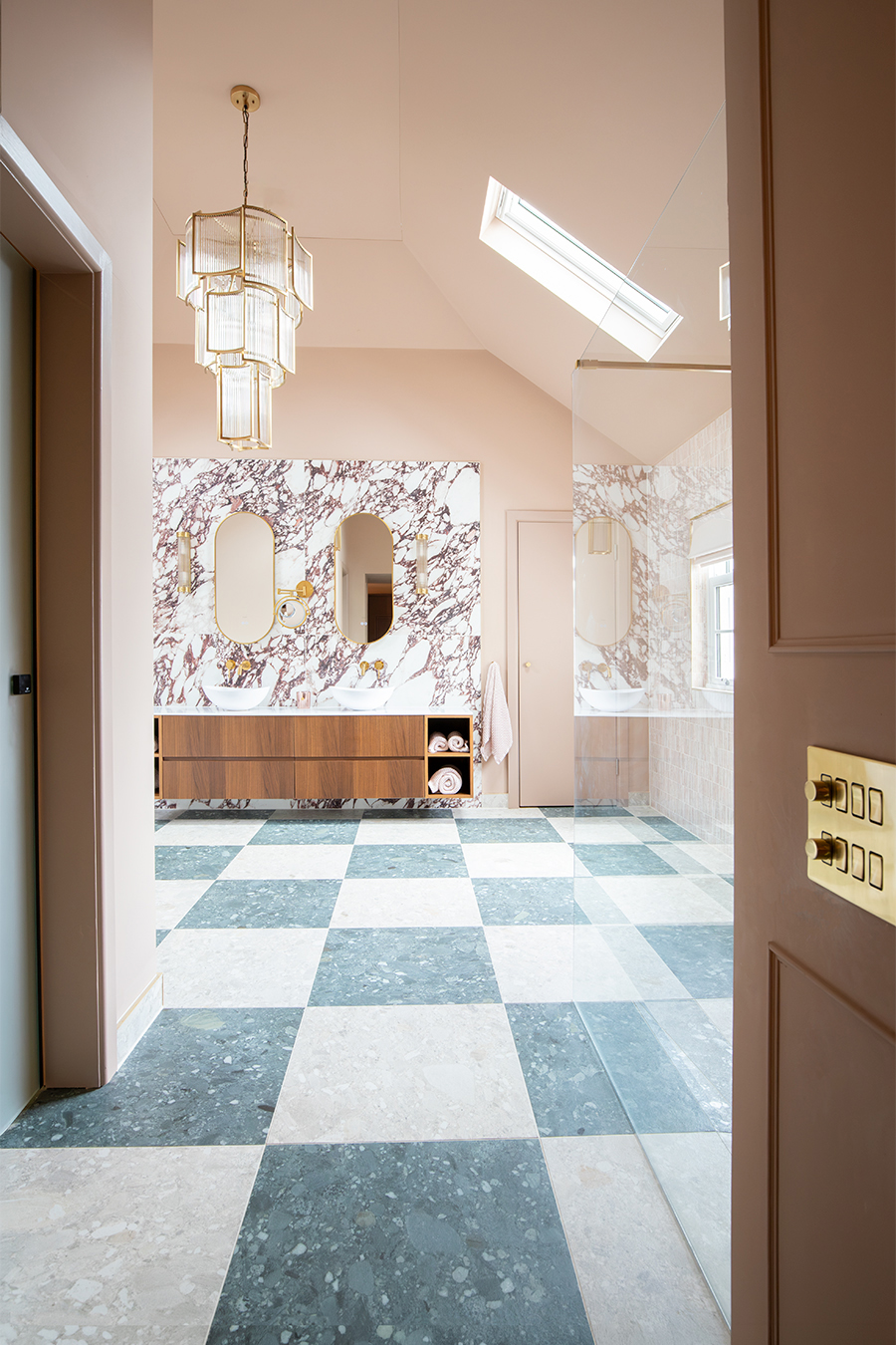 A photo of the en suite taken through the opening from the dressing room, showing the full height of the brass and glass chandelier.