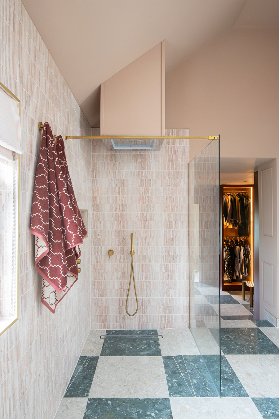 A photo of the en suite showing the wet room shower with rainfall head and chequerboarrd tiles.
