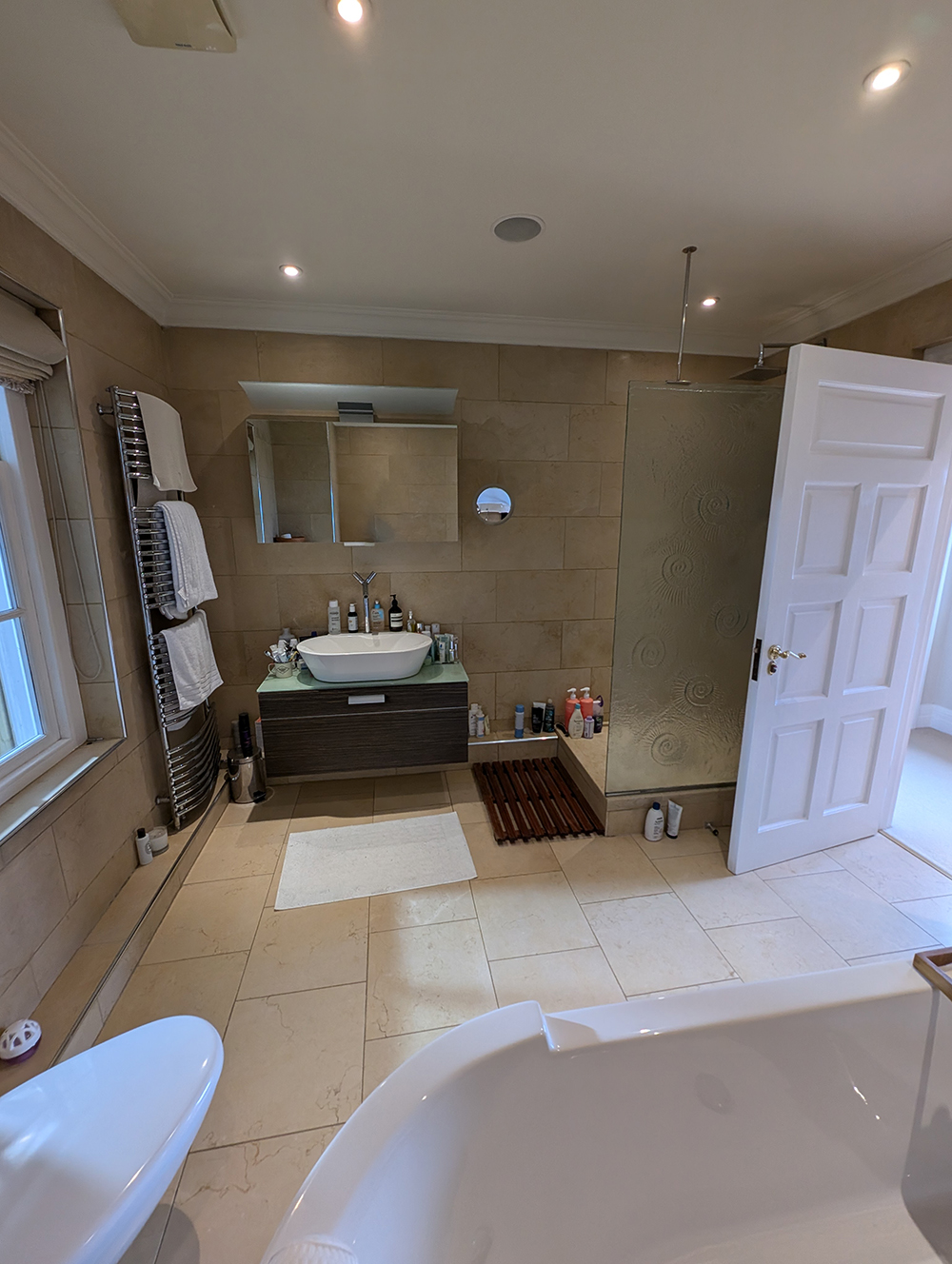 A photo of the previous en suite which had floor to ceiling beige tiles and chrome fittings. 