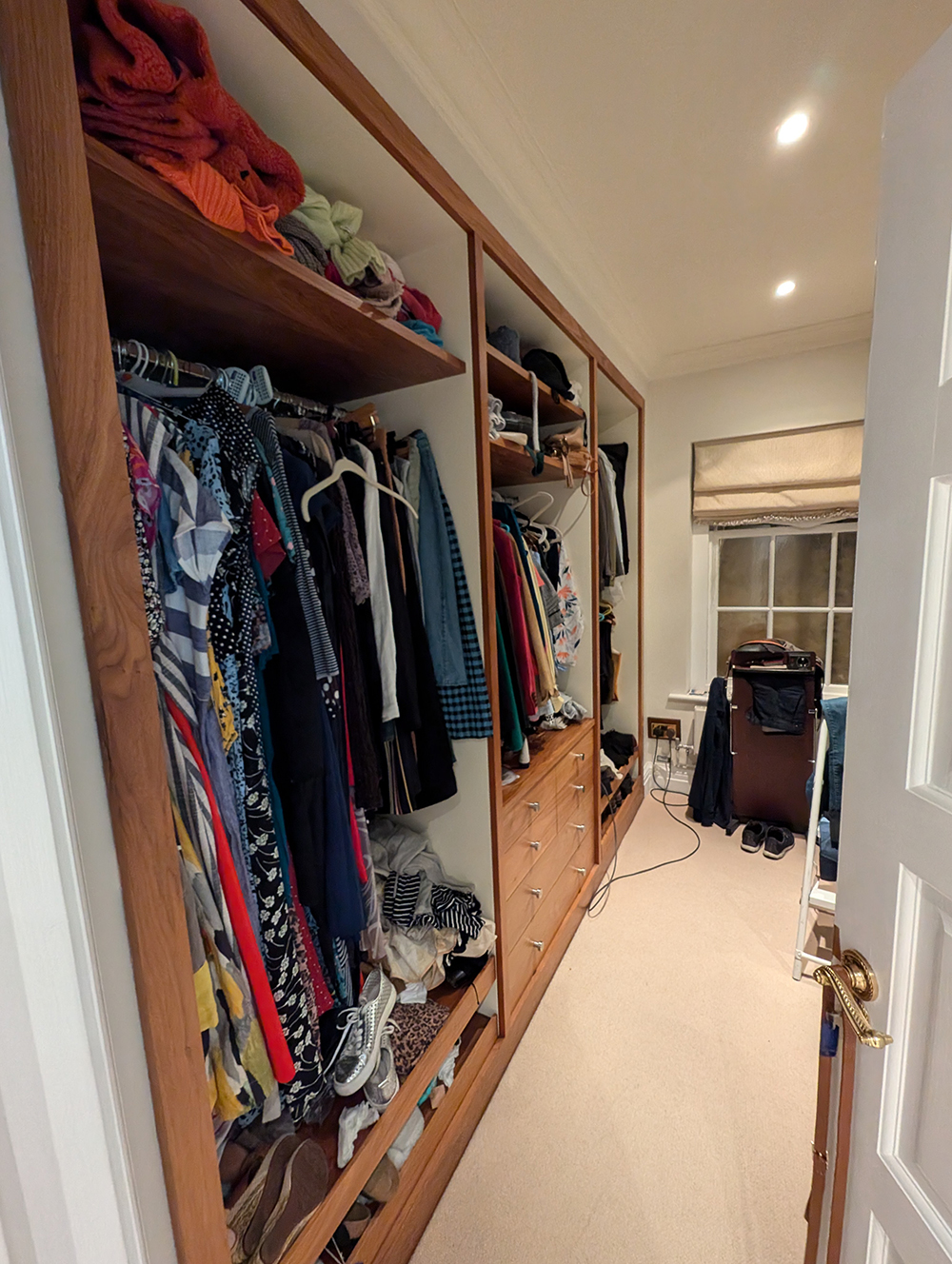 A before photo of the previous dressing room which is long and narrow, with shelving on one side only.
