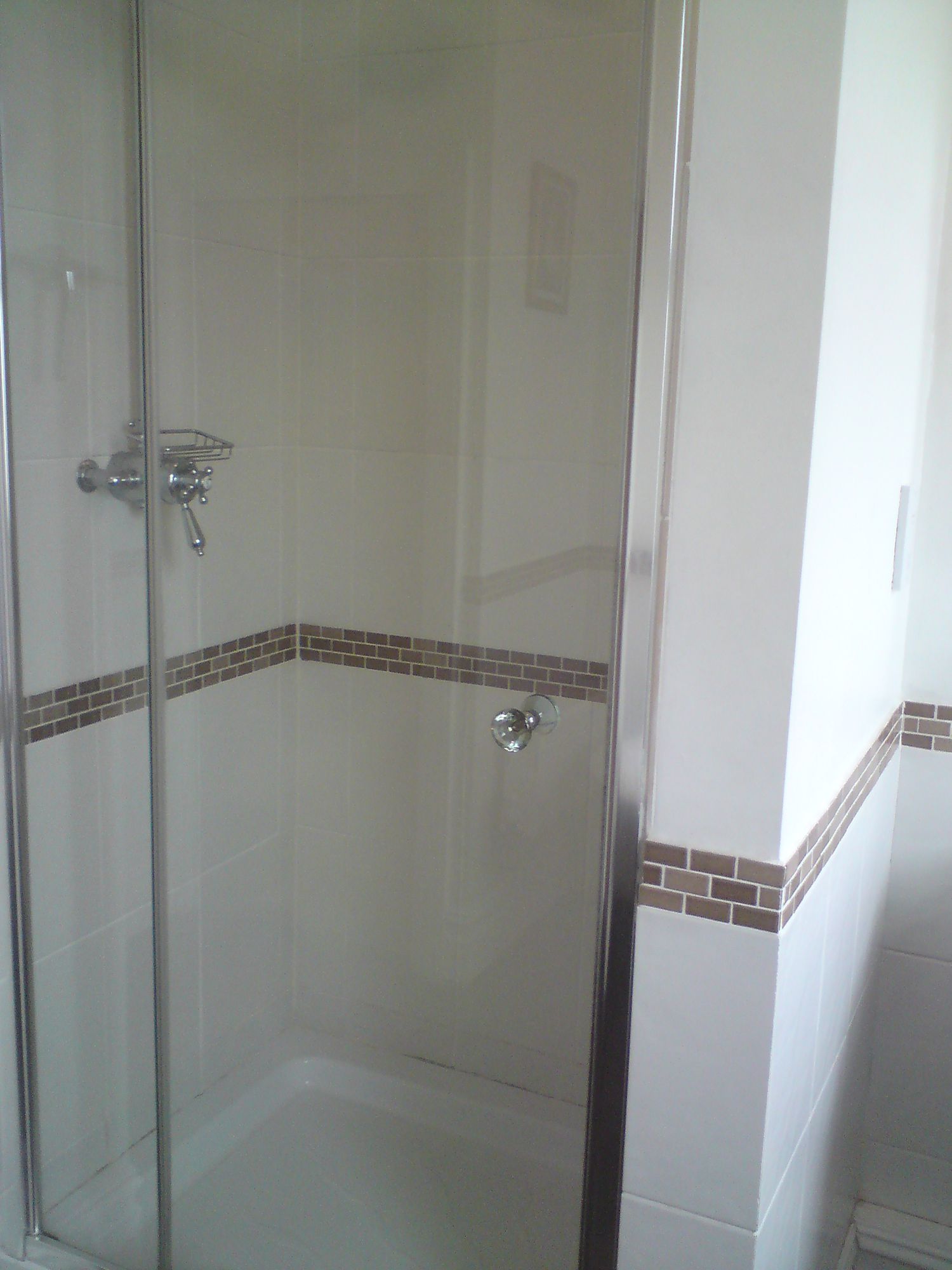 The old enclosed shower area with a glass door on a built in cubicle.