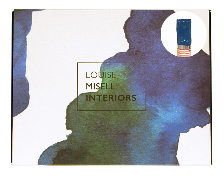 A photo of the outside of the Designer in a Box with a small paintbrush showing a dark blue paint colour.