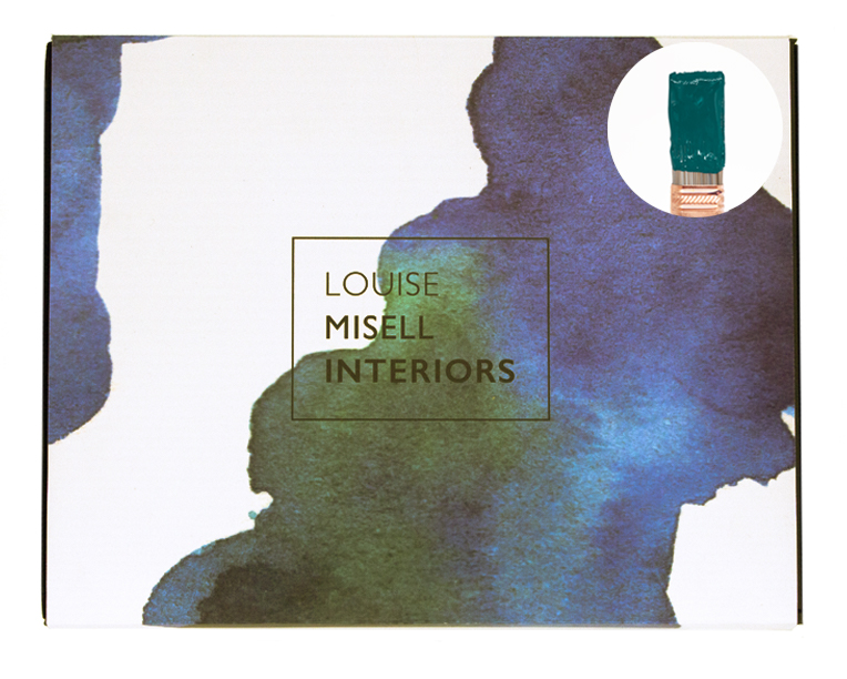 A photo of the outside of the Designer in a Box with a small paintbrush showing a dark teal paint colour.