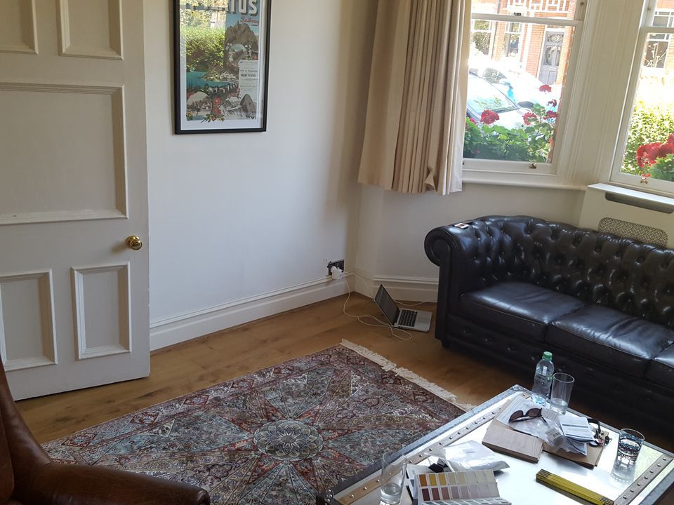 A before photo showing a leather sofa and plain white walls.