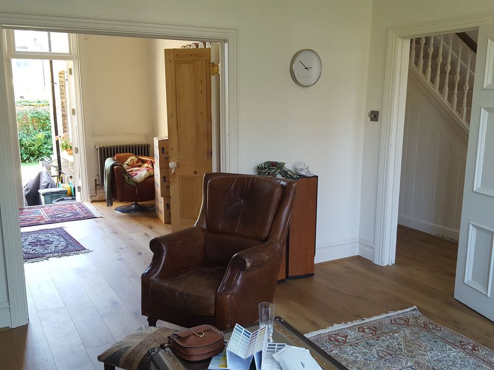 A before photo showing the view from one room to another, with white walls and mismatched furniture.