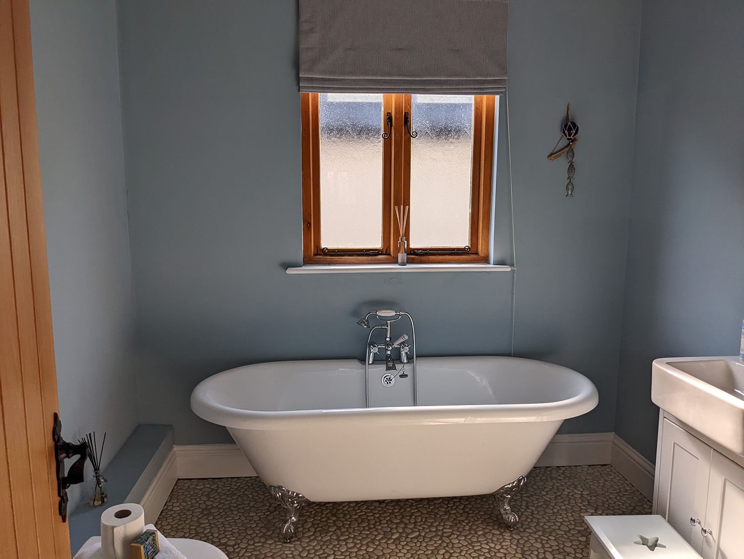 A before photo of the family bathroom which had bare blue walls and an ill fitting blind.