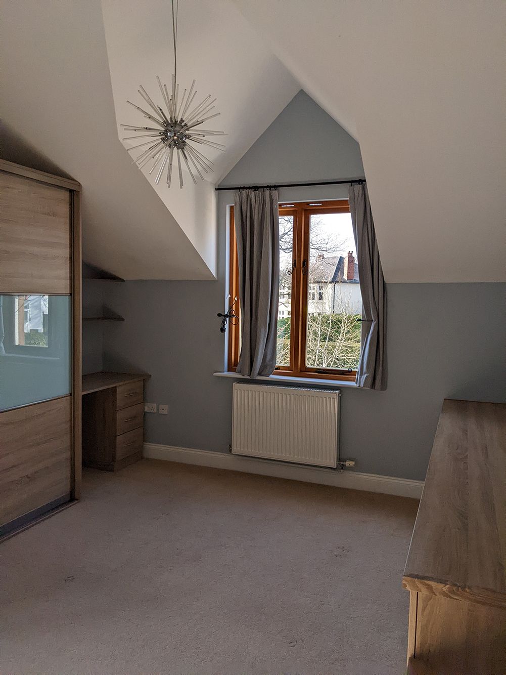 A before photo of the child's bedroom showing the cold blue walls and short striped curtains.