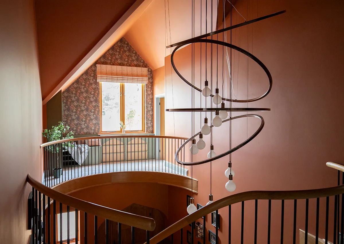 A photo of the mezzanine landing with a large bespoke and unique chandelier hanging down the middle.