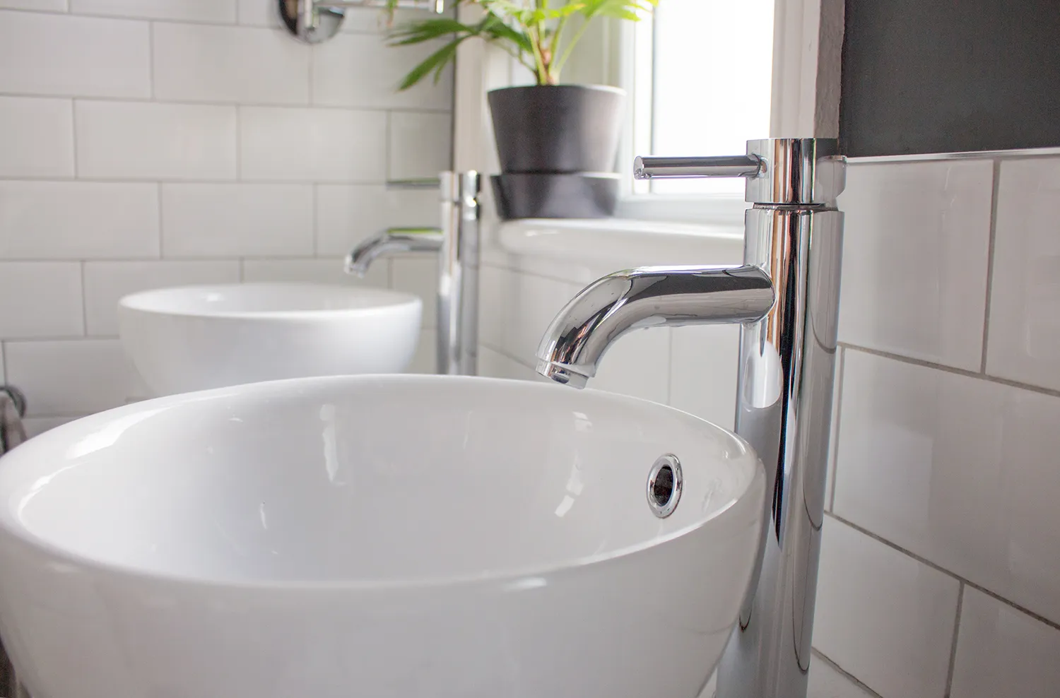 A close up of the two sinks with their tall chrome taps next to them.