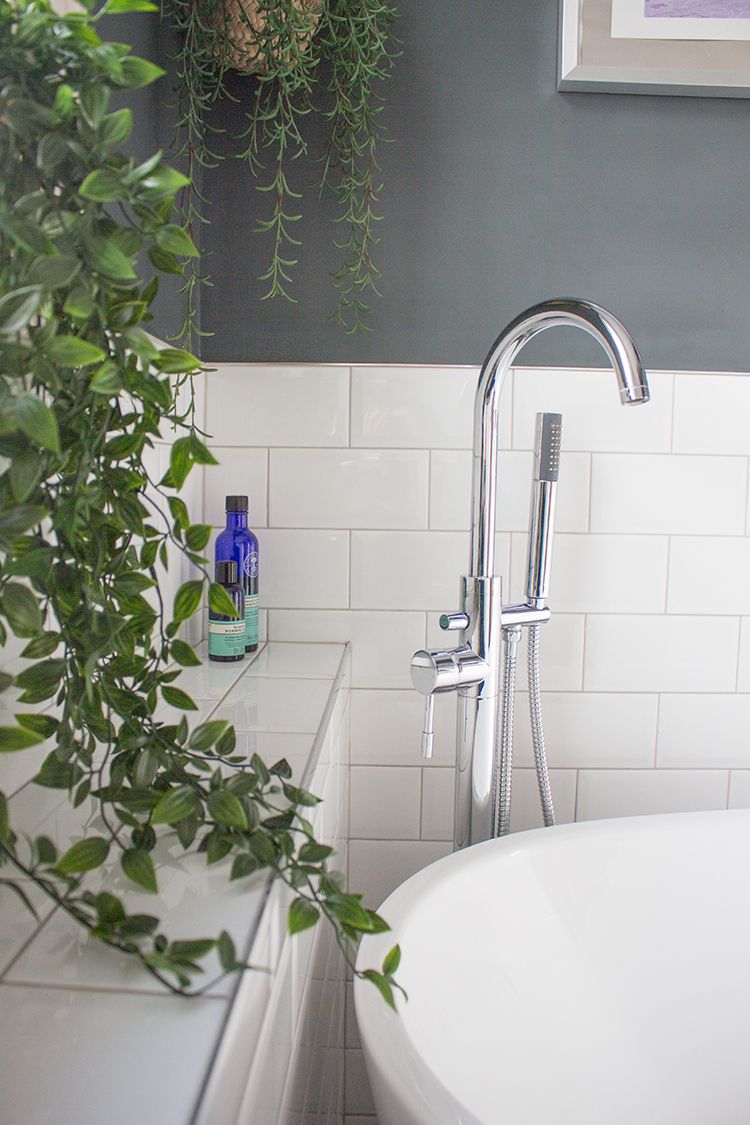 A close up of the standpipe bath tap and shower head, seen through the plant hanging over the window sill.