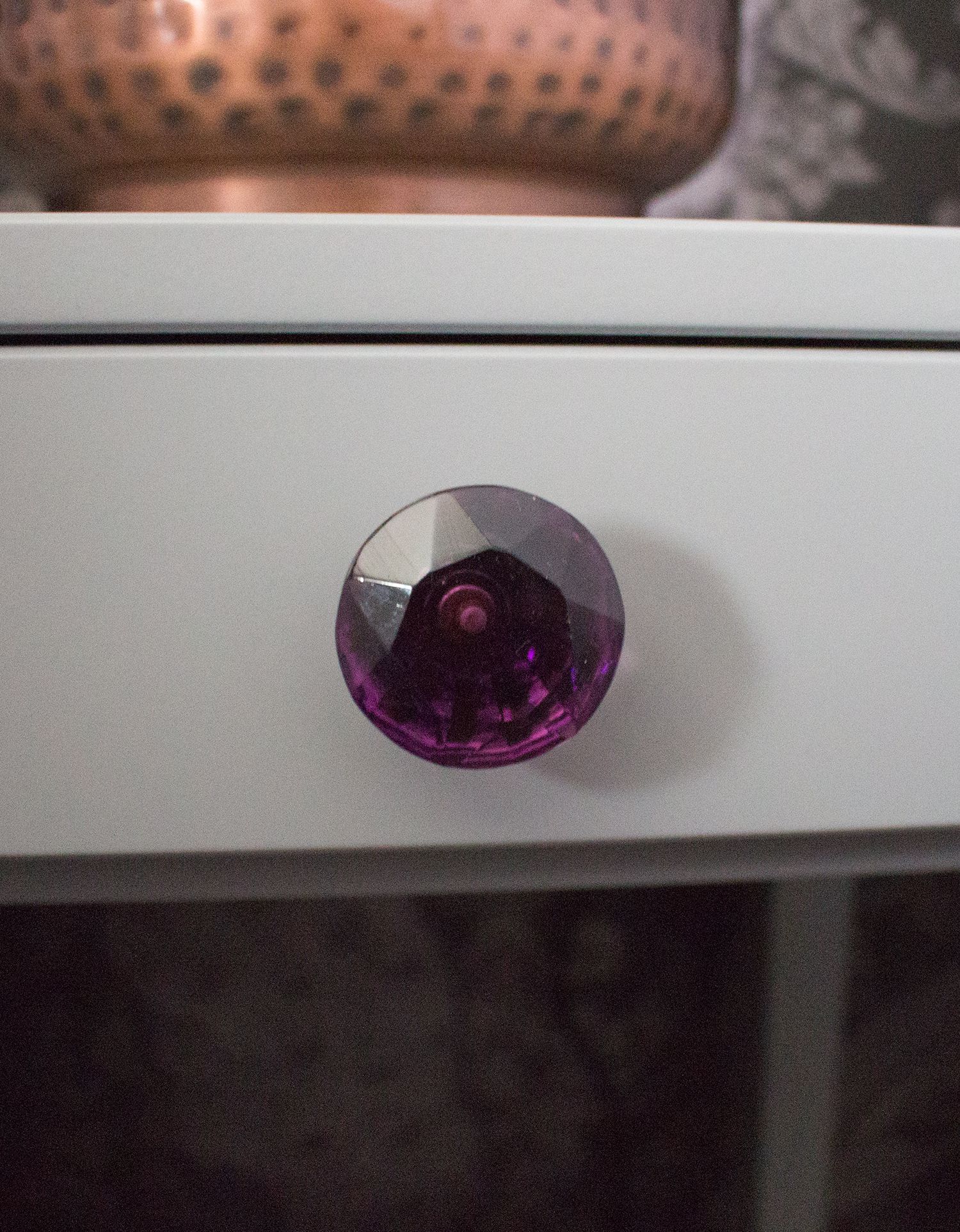 A close up of one of the new bedside tables with the new purple glass handles added.