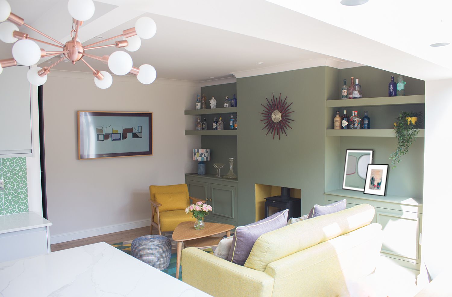 A view of the green painted built in shelving, with the Frame TV on the wall, and the sofa and yellow armchair.