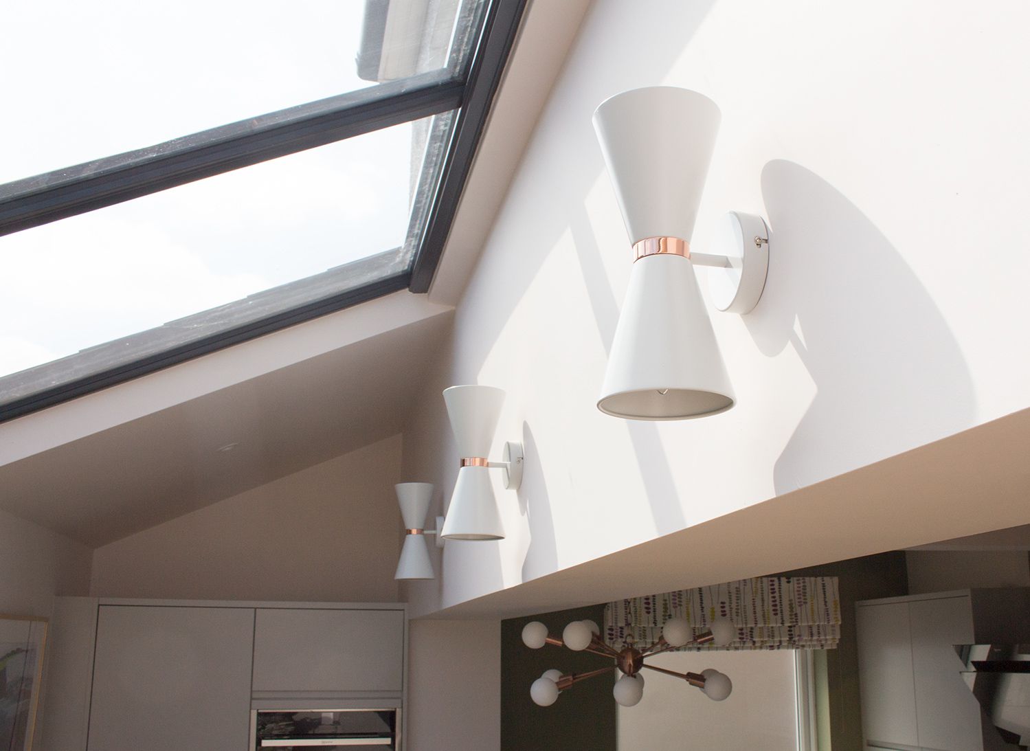 A photo of the three wall lights in the extension area, with the glass roof above.