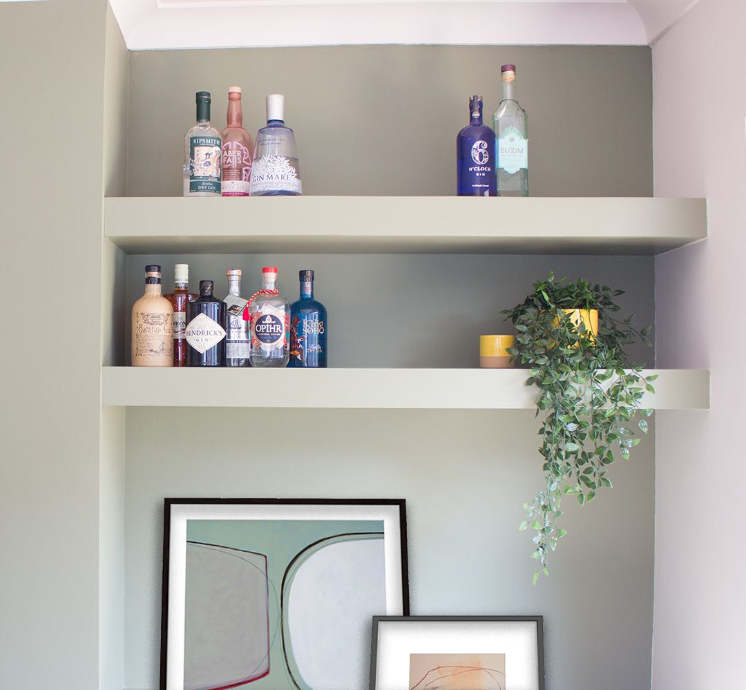 A close up of the built in shelves styled with gin bottles, a plant and artwork.