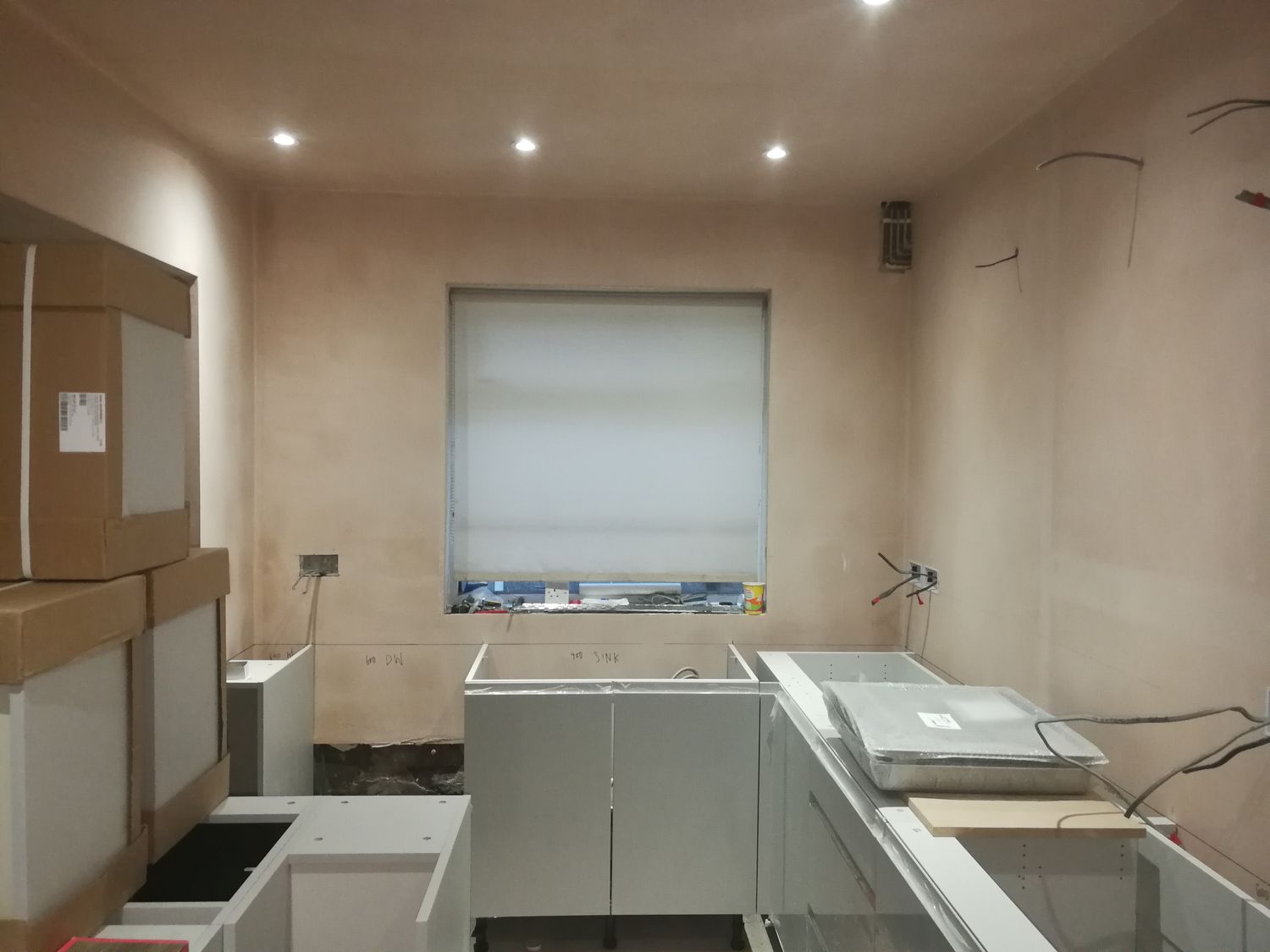 A photo of the kitchen area with the old window, bare plaster walls and no window dressing.