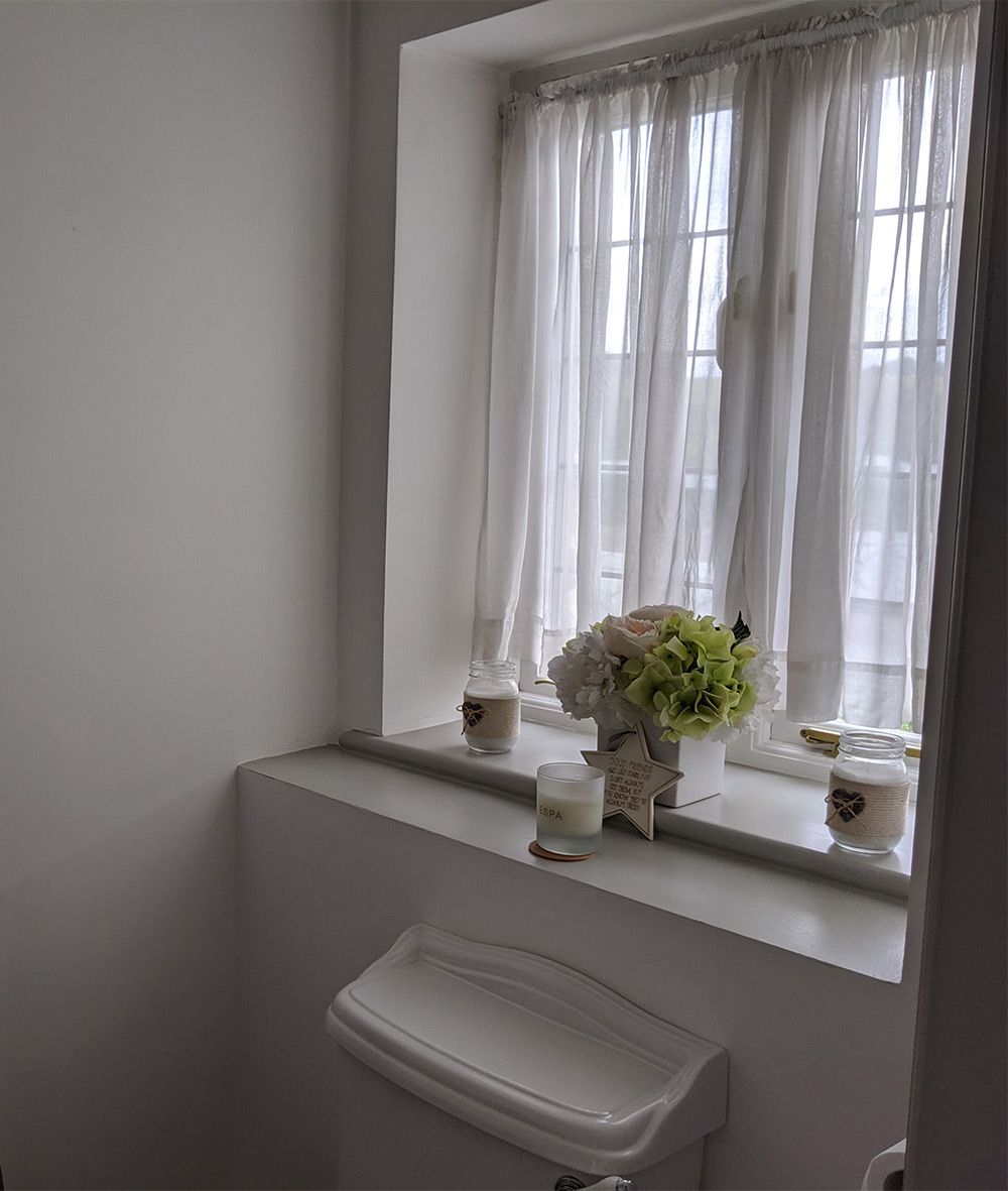 A photo of the loo before, with net curtains and a traditional style WC.