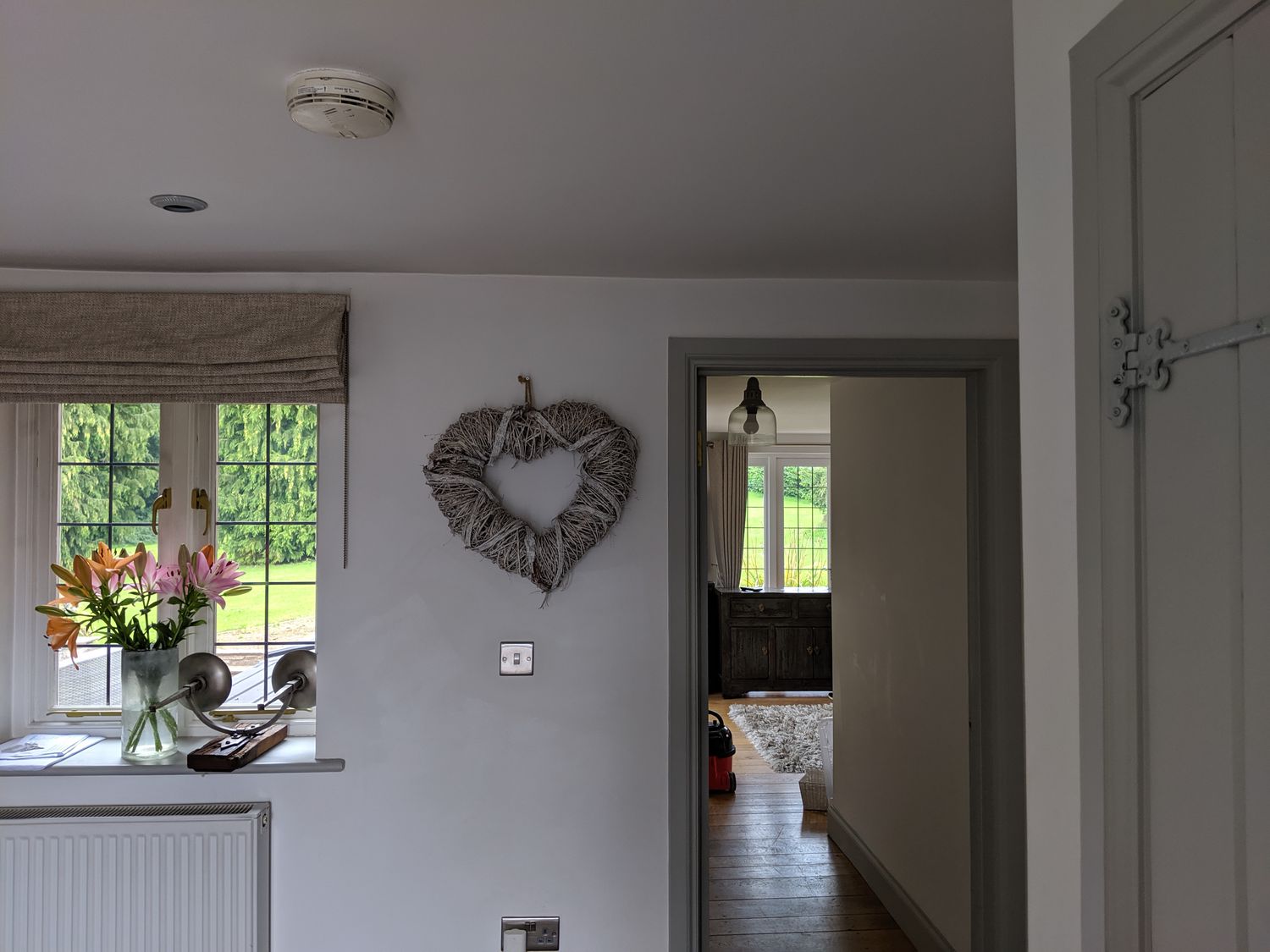 The window in the hallway before, with a grey blind and a grey heart on the wall.