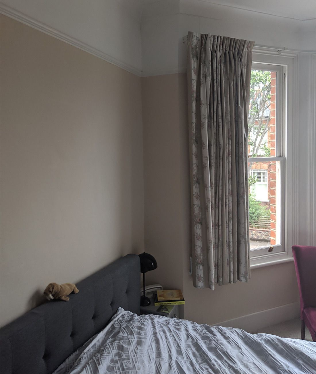 A view of the room showing the beige walls and too short curtains.