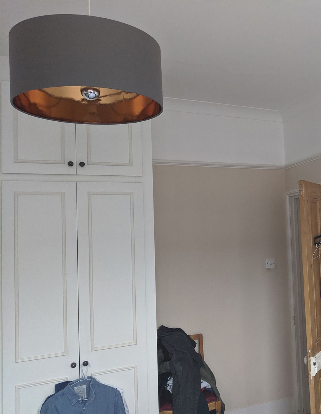 A before photo of the old grey lampshade and the white melamine wardrobes.