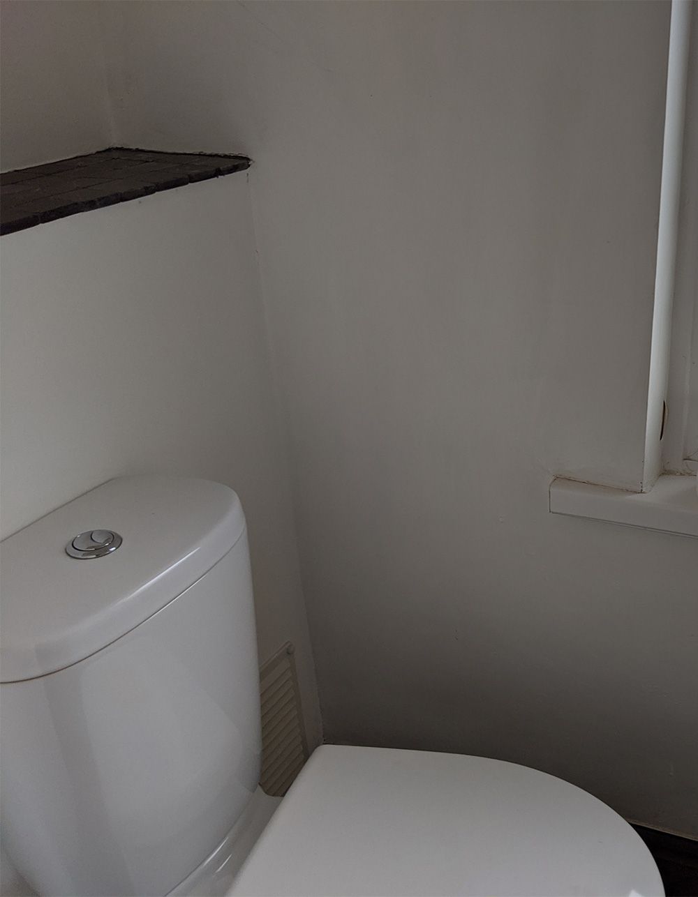 A photo of the old loo with no tiling around it and white walls.