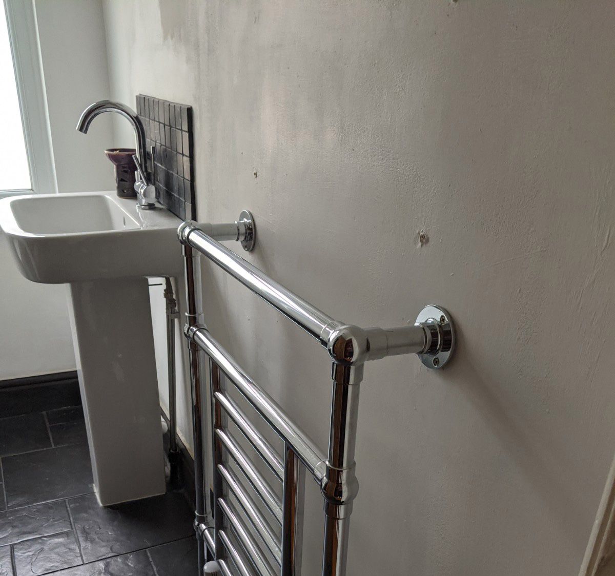 The white pedestal sink and chrome towel radiator in the en suite before the room as redesigned.