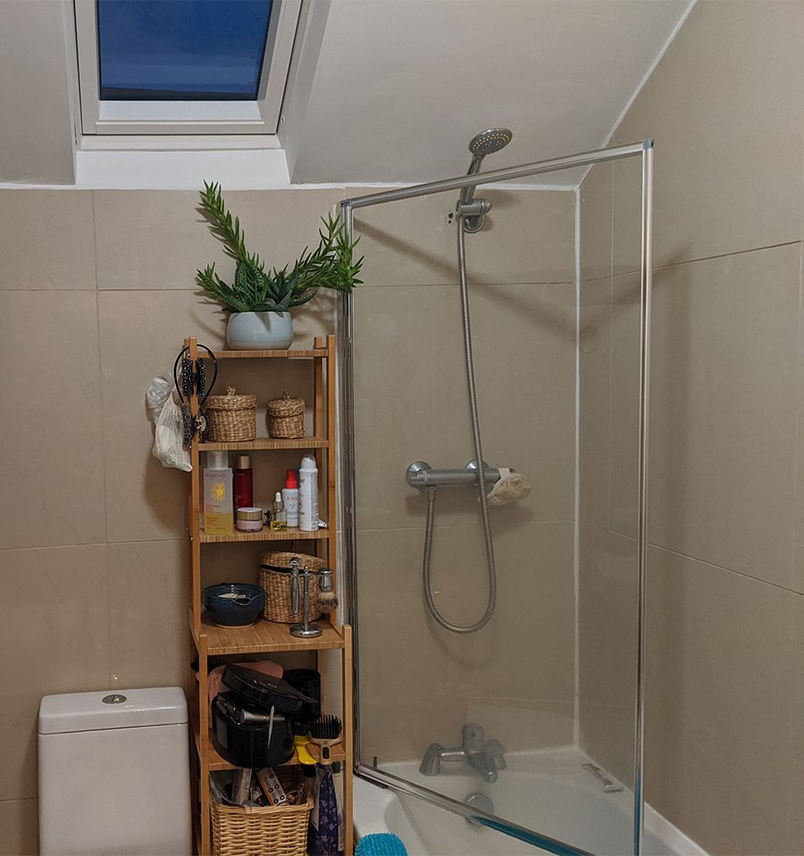 The old shower with a small shower head and dirty shower screen.