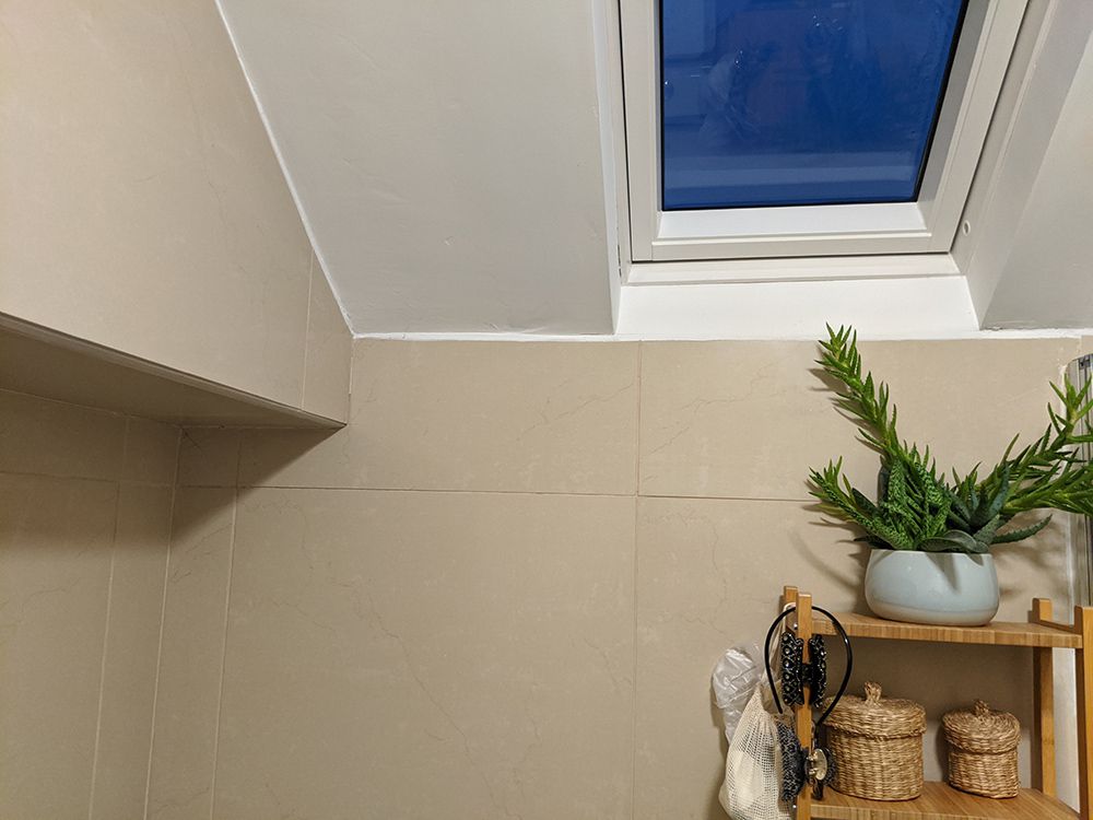 A photo of where the sink recess is, with the beige tiles and old shelving unit.