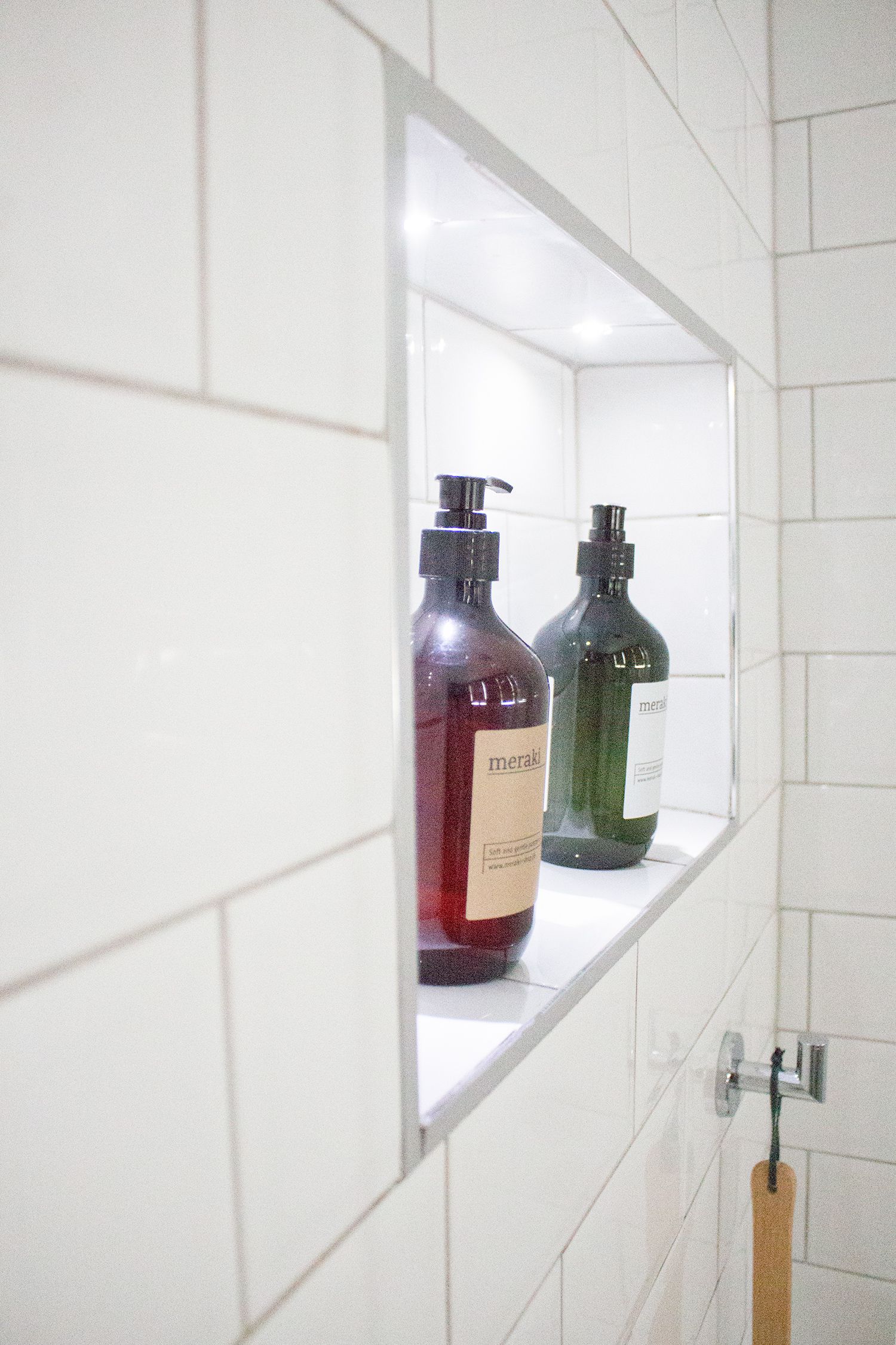 A close up of the shower niche with lighting inside, showing off the nice body wash bottles.