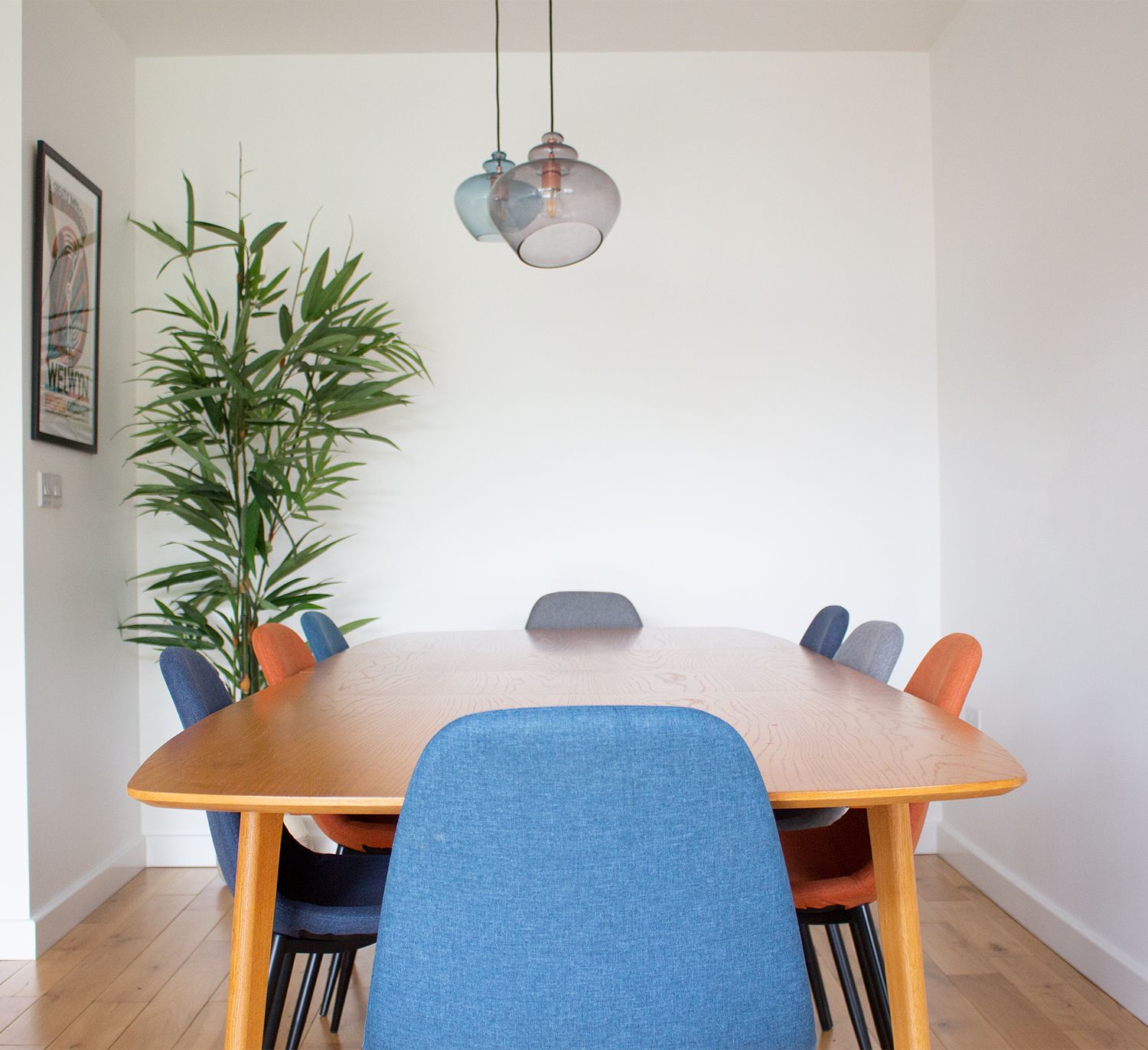 A photo of the mid century style dining table with upholstered chairs in blue, orange and grey.