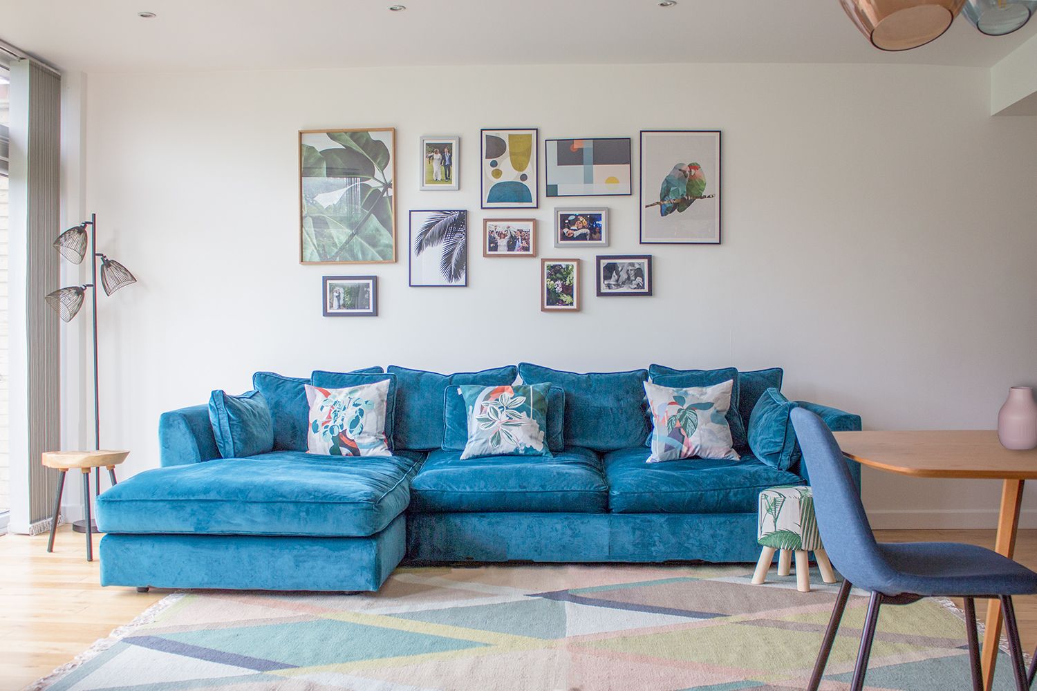 A photo of a teal velvet sofa in a room painted off white and on a colourful geometric rug.